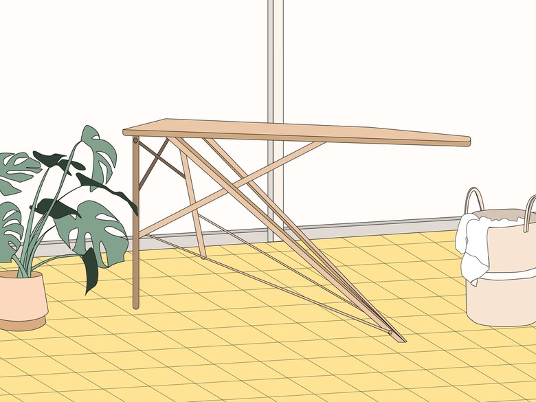 An illustration of a fold-out light brown ironing board on a yellow floor next to a basket of laundry.