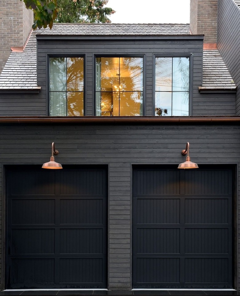 black exterior with black garage doors and copper wall sconces