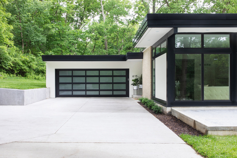 midcentury home with black garage doors with window panes