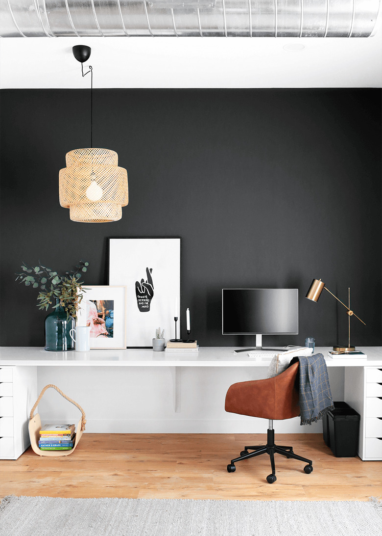 black home office with accent wall, woven light fixture hanging above the white wall-mount desk