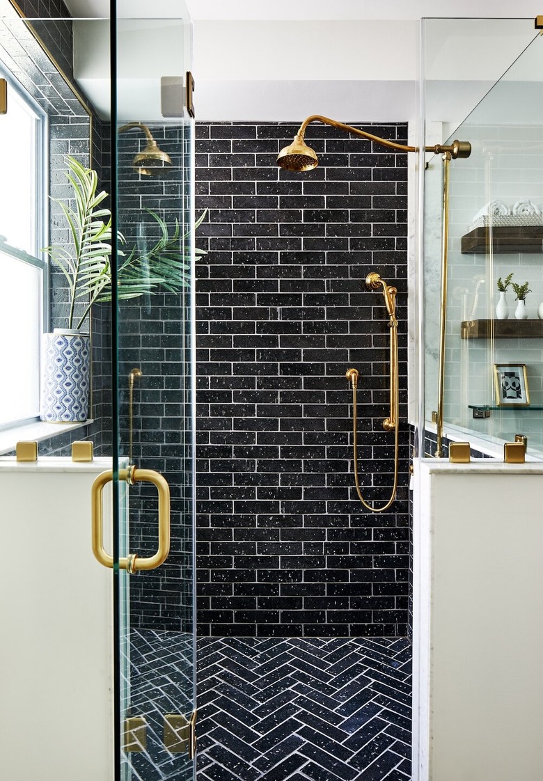 contemporary black tile shower and white grout and brass fixtures