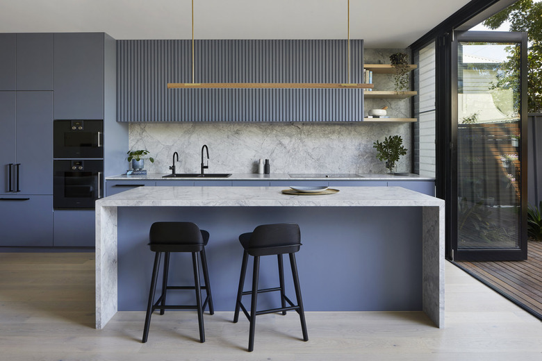 blue and gray kitchen idea with waterfall island countertop and marble backsplash