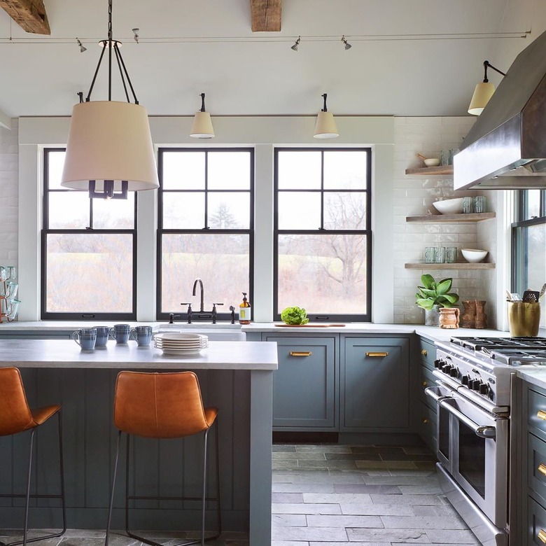 Blue and gray kitchen with leather bar stools and slate floor