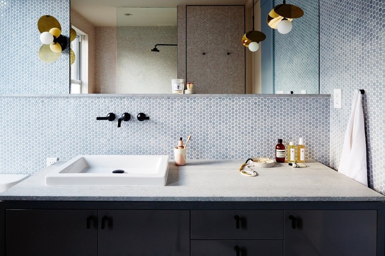 blue bathroom backsplash with penny tile mosaic and wall mounted faucet