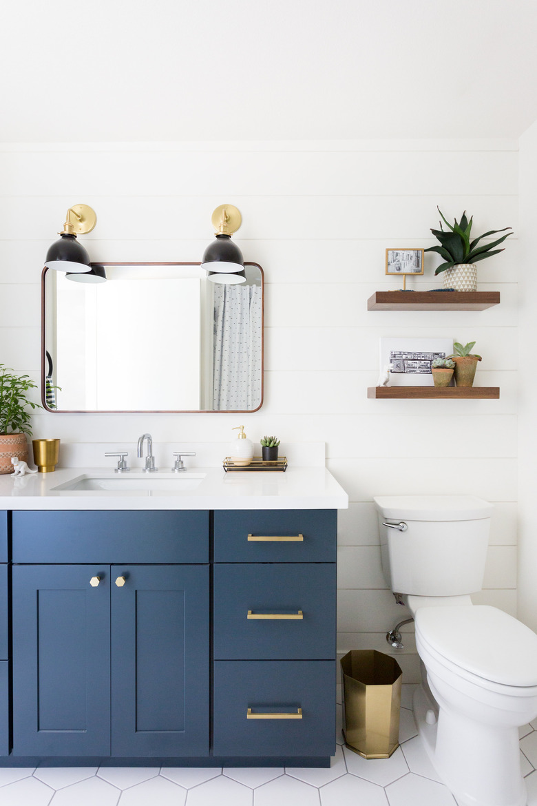 white and blue bathroom cabinets with wooden and brass accent