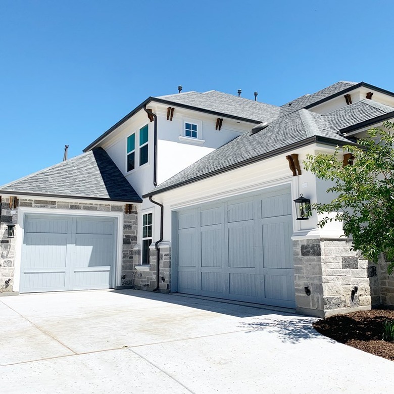 white and stone house with light blue garage doors