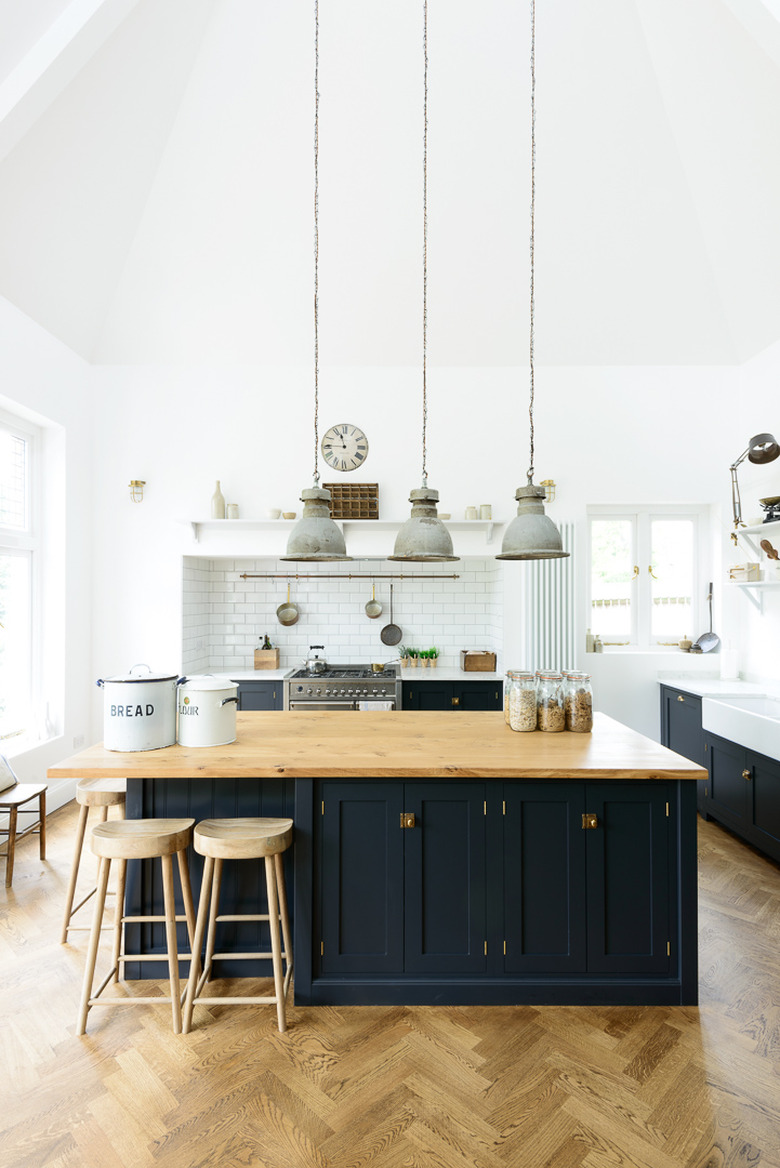 navy blue kitchen island with wood countertop and herringbone flooring