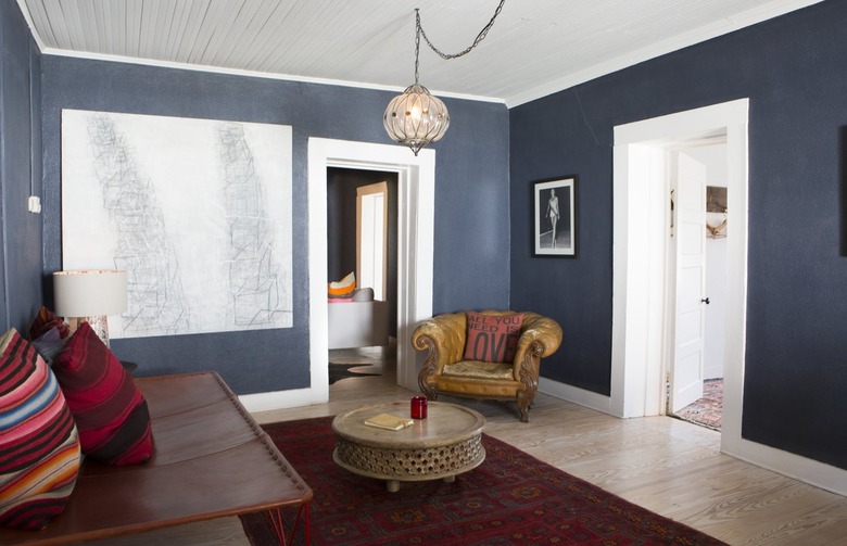 Bohemian blue walled living room with red rug accents and wood floor