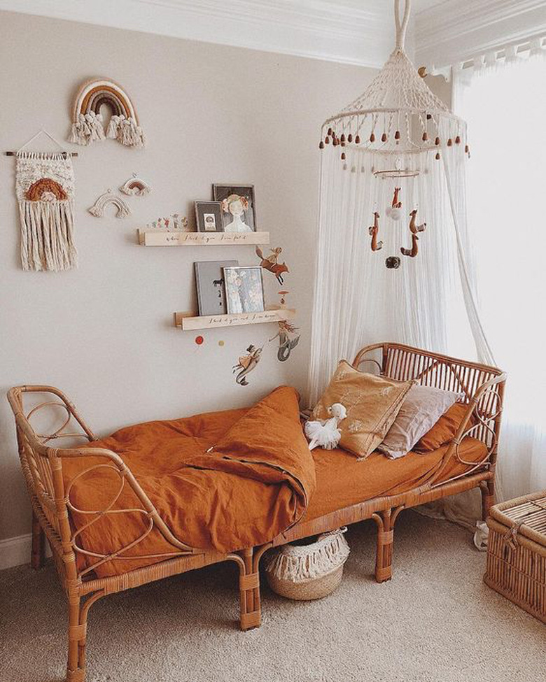 bohemian kids bedroom idea with canopy hanging from ceiling and rust bedding