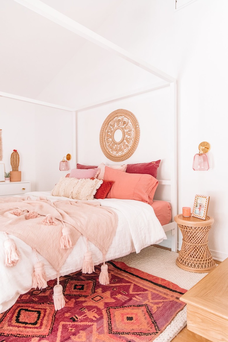 bohemian bedroom lighting idea with colorful pink wall sconces on either side of canopy bed