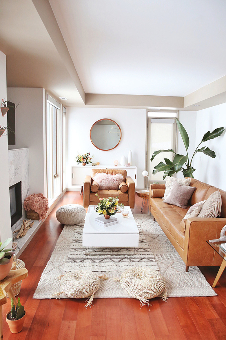 Boho apartment decor in living room with leather furniture and woven floor cushions