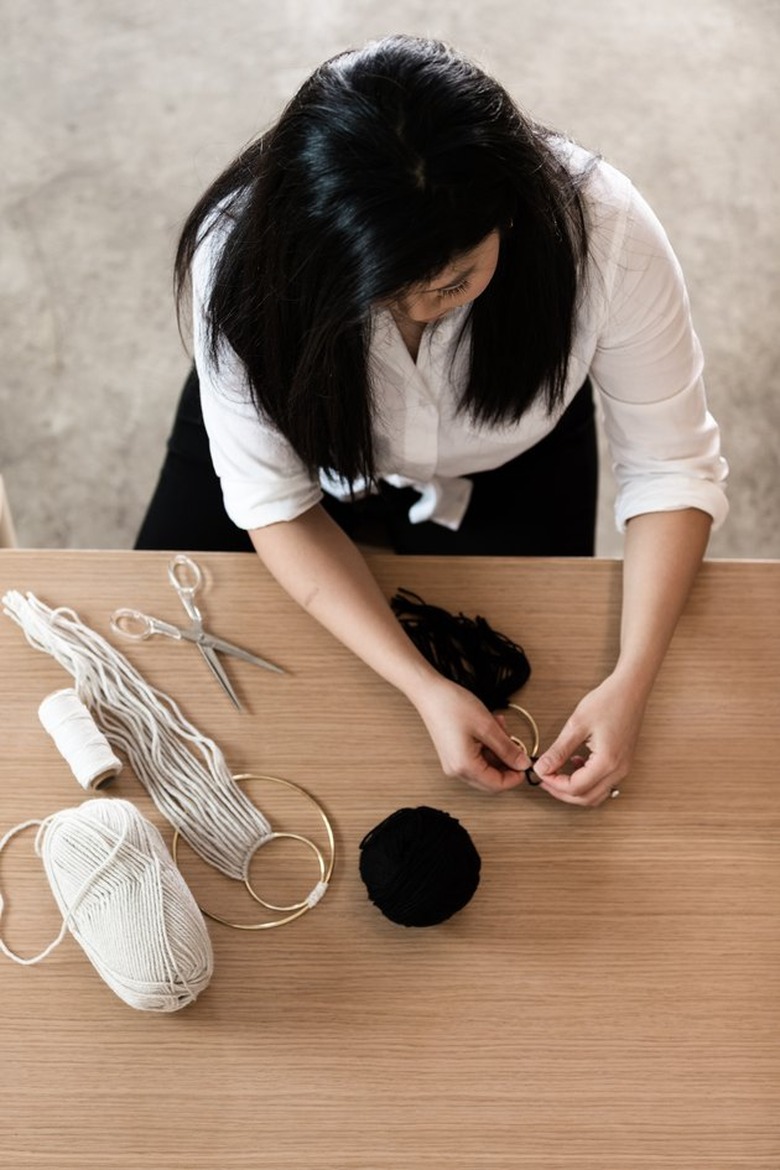 woman working on a yarn wall hanging