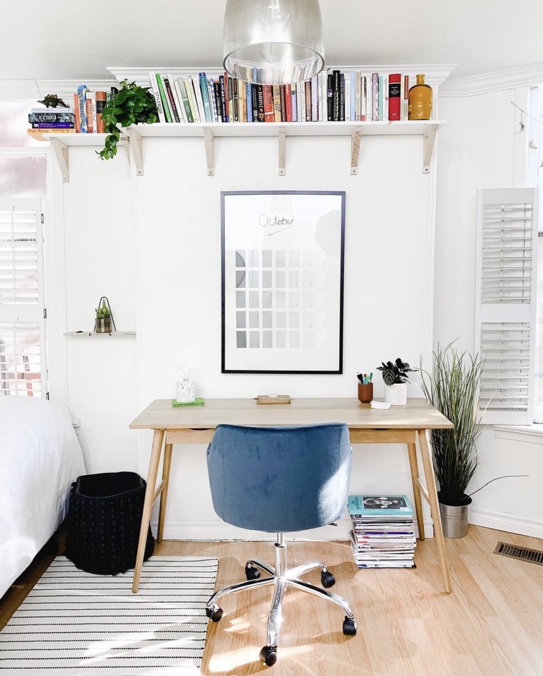 book storage in a room with a desk with a blue chair sits below a wall-mounted bookshelf.