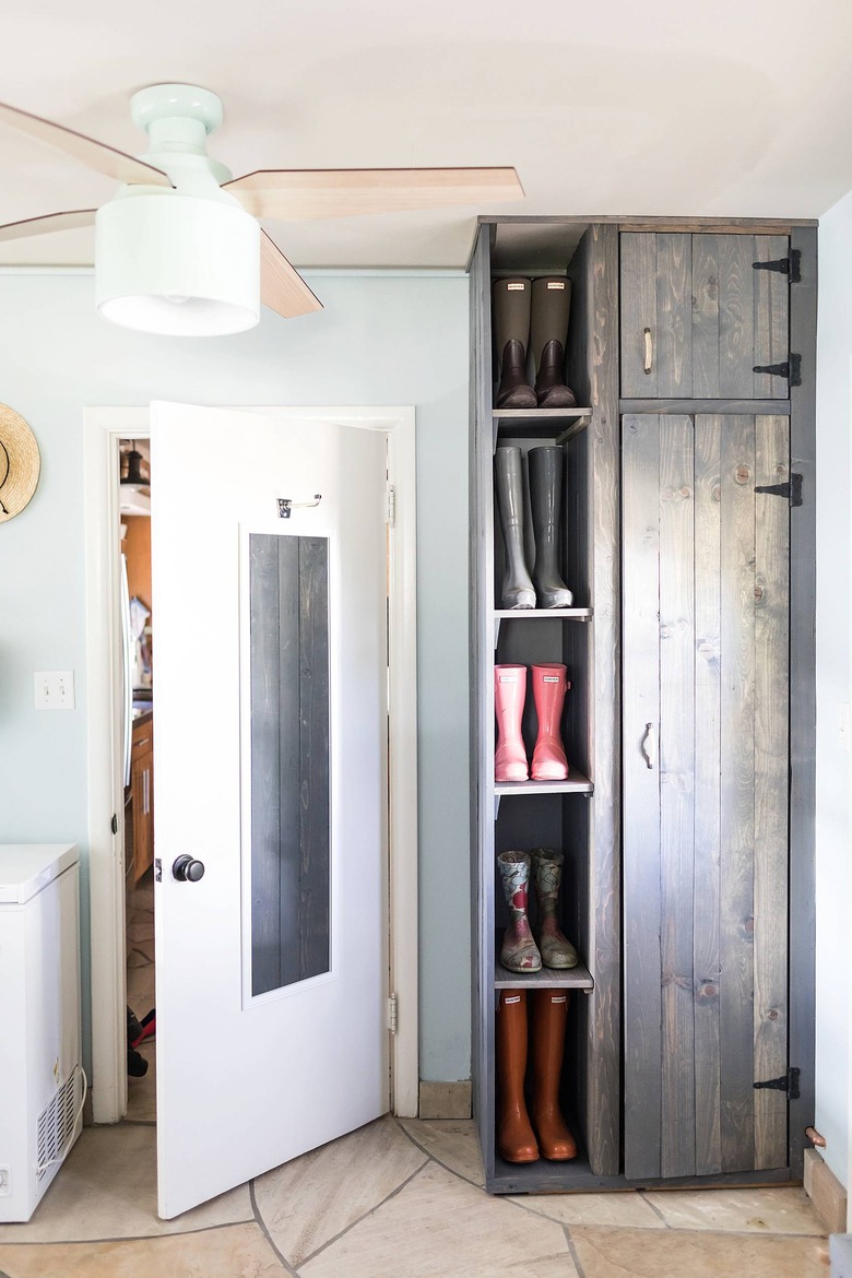 boots shelved in a standing cabinet in a laundry room