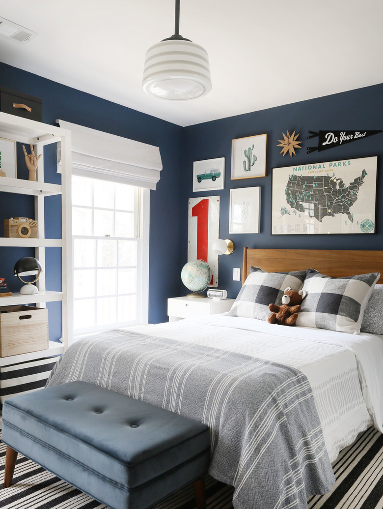 navy blue boys bedroom idea with gallery wall above wooden headboard and bench at foot of bed