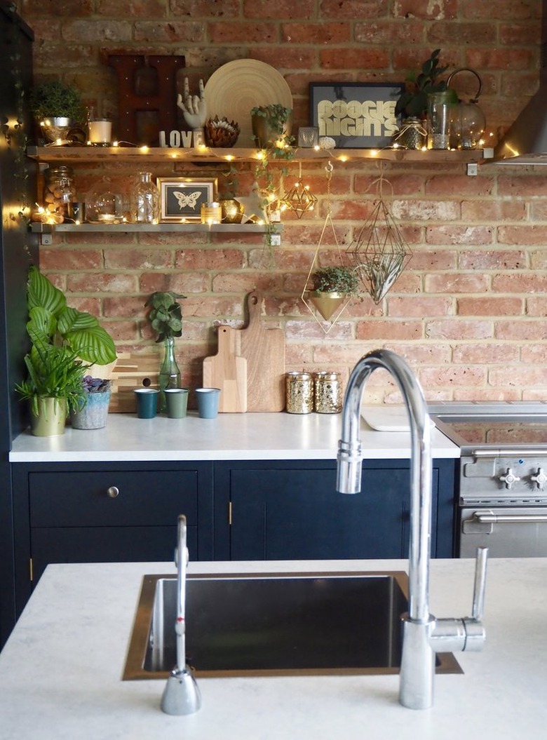 Fairy light alternative kitchen lighting idea with open shelving and blue cabinets