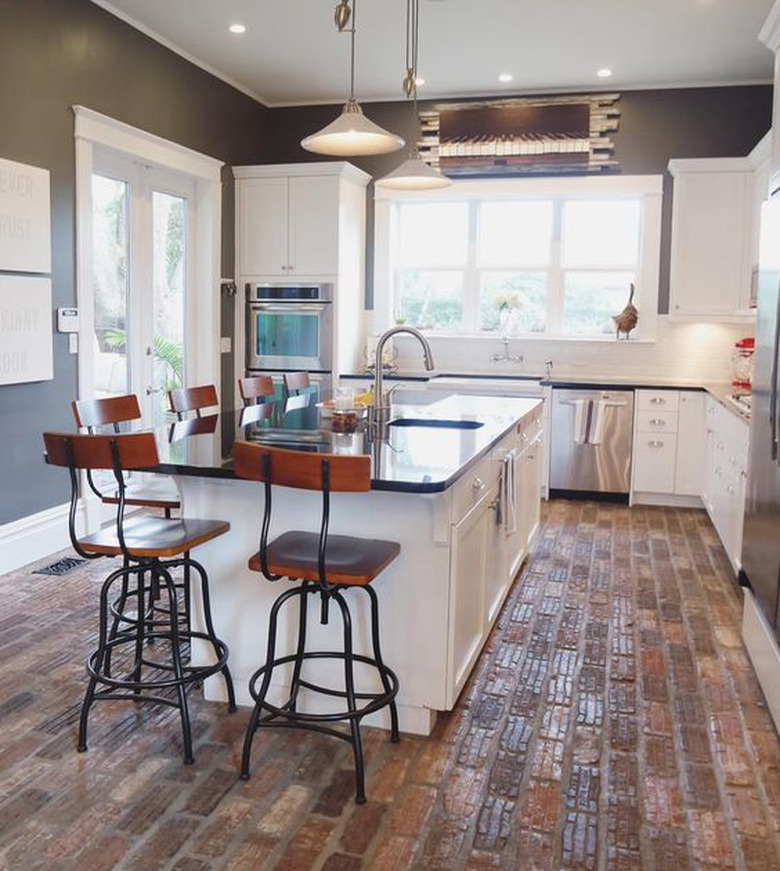 industrial kitchen with white cabinets and brick flooring