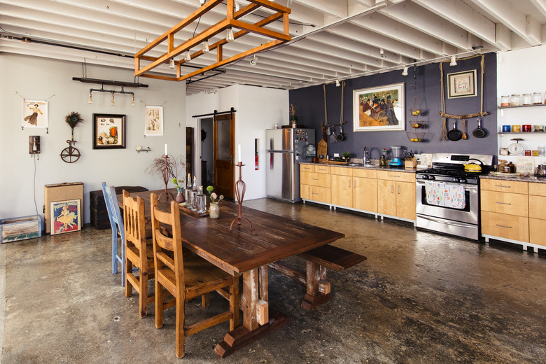 Concrete flooring in eclectic kitchen with light wood cabinetry and open shelving