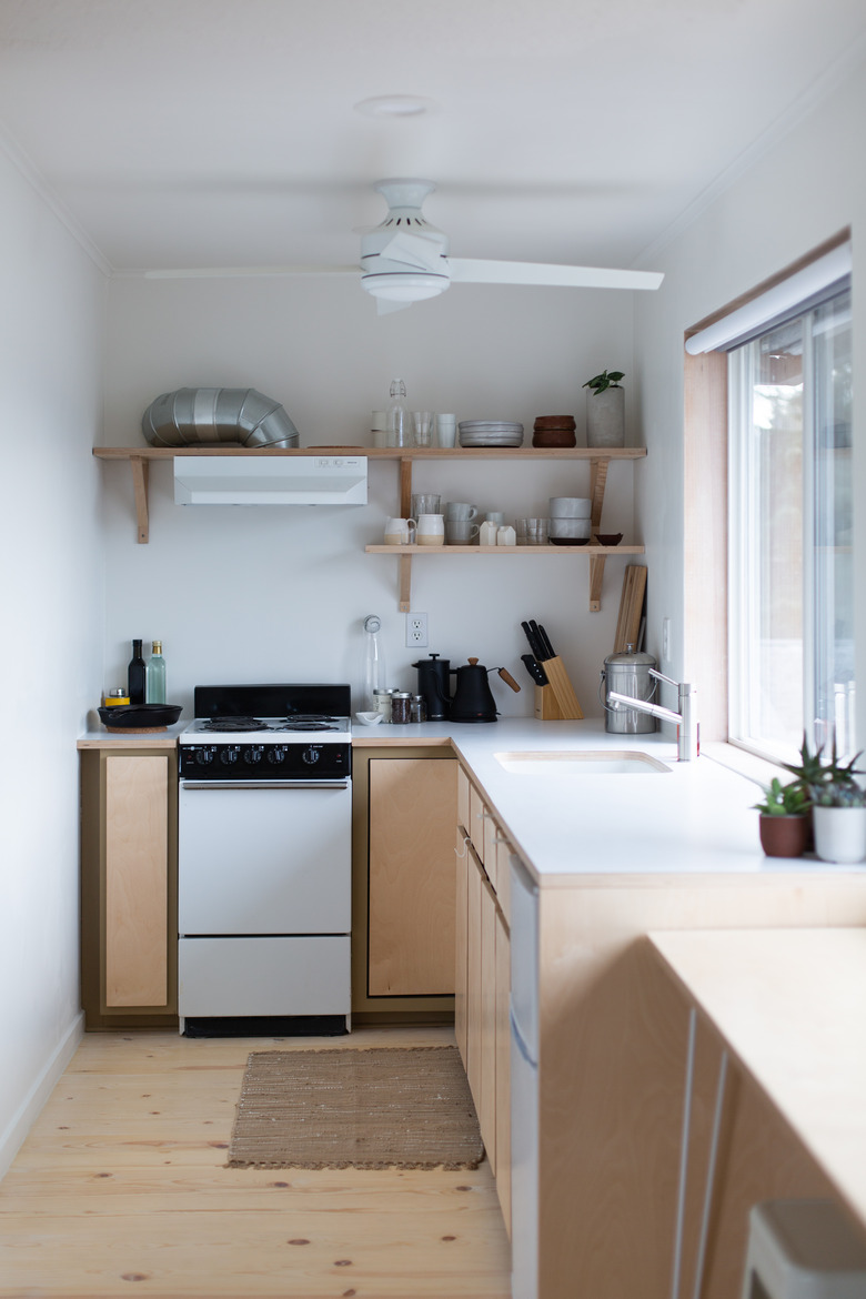 Compact kitchen with open shelving and pale wood floors with ceiliing fan