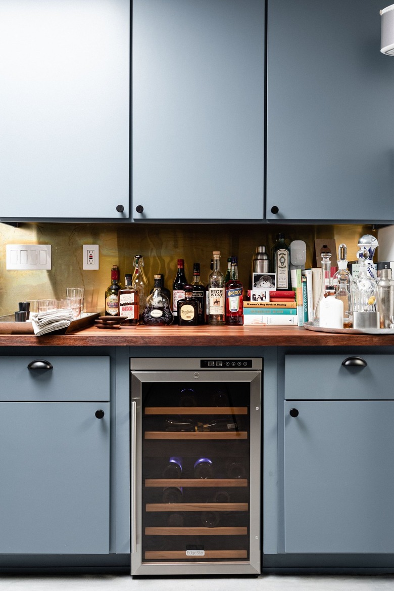 Kitchen with blue cabinets, wine refrigerator, wood counters, bar.