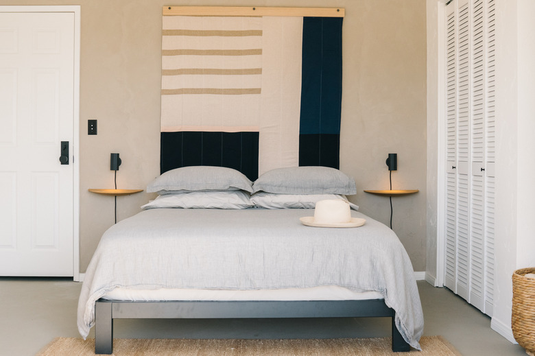 tan bedroom decorated with calming colors and bold geometric wall art piece.