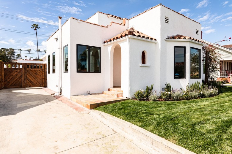 A mediterranean-style house with a yard full of green grass