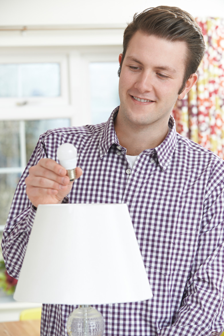 Man putting LED lightbulb into lamp.