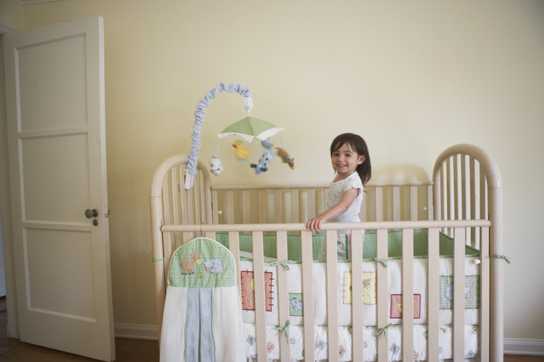 Toddler girl standing in her bedroom crib