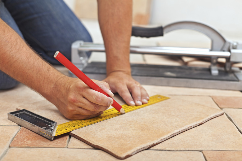 Laying ceramic floor tiles - man hands closeup