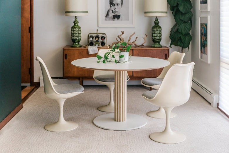 White Scandinavian round table with mid-century decor in white wall carpeted room