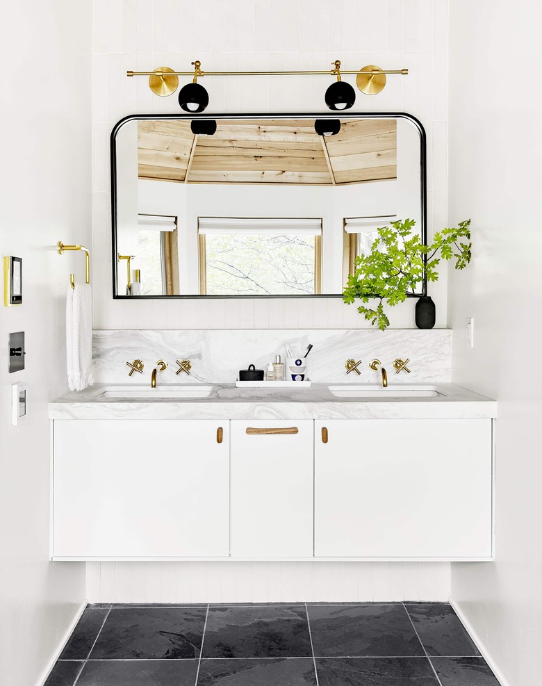 bathroom space with black floor, white cabinets, and one large mirror