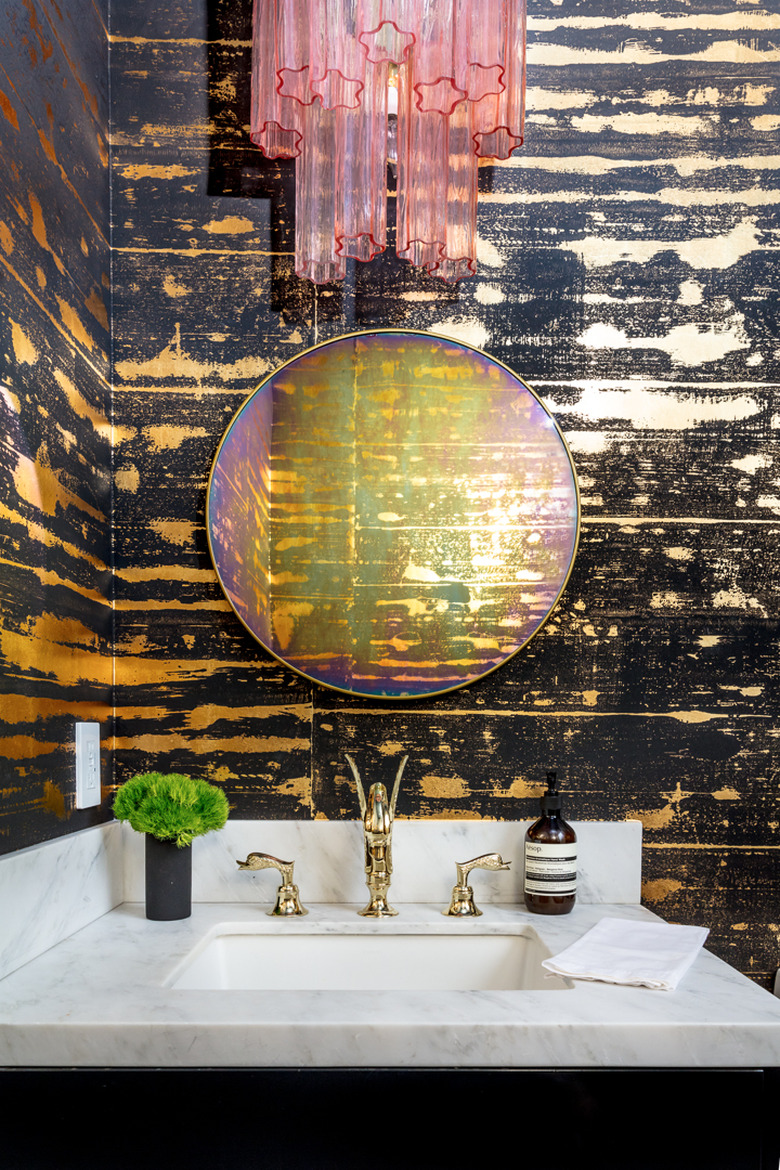 bathroom with textured wall, pink lighting fixture, and marble backsplash