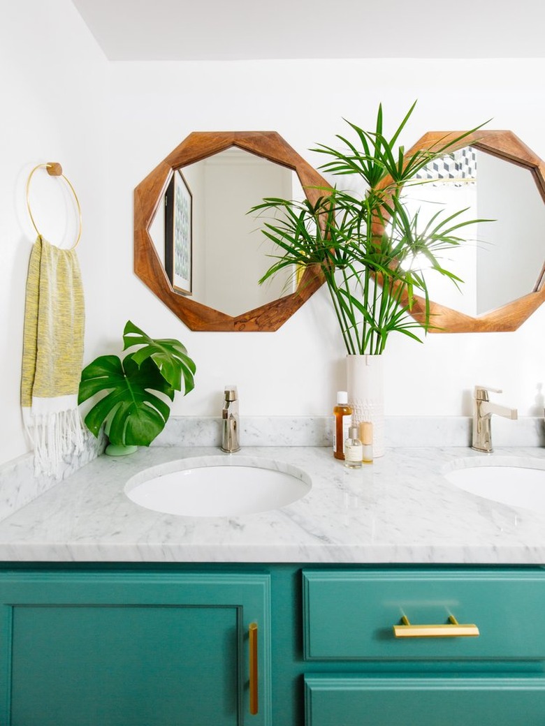 bathroom space with bright cabinets and two wooden mirrors