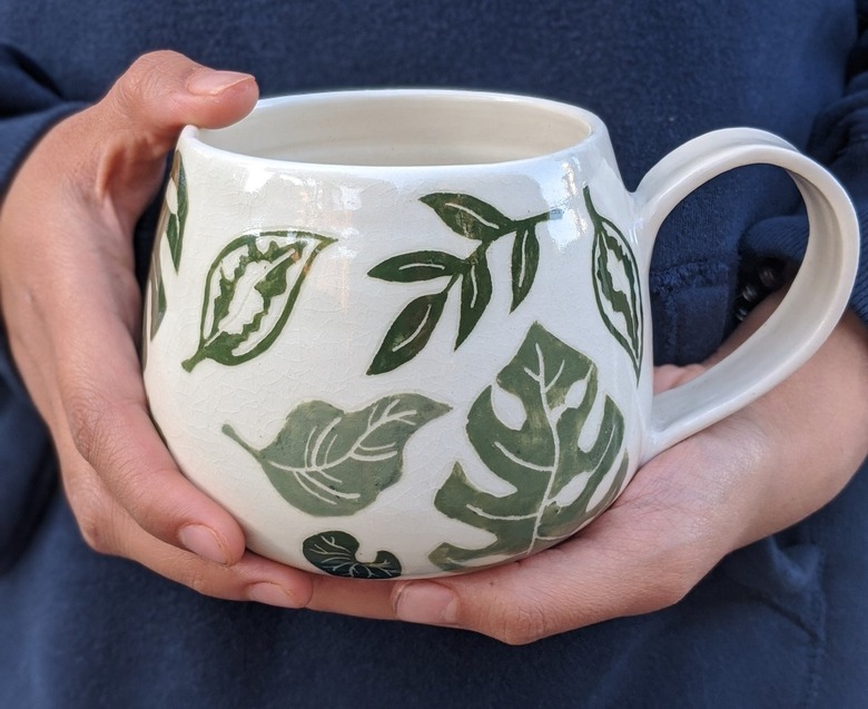 mug with plant pattern being held in a person's hands