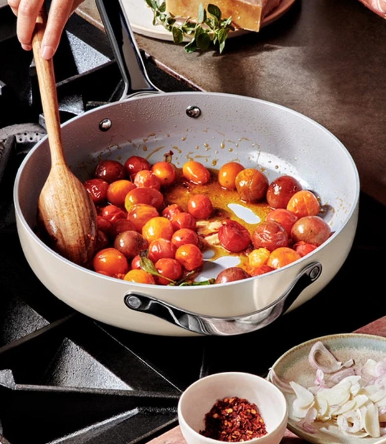 White ceramic pans with tomatoes on cooktop.