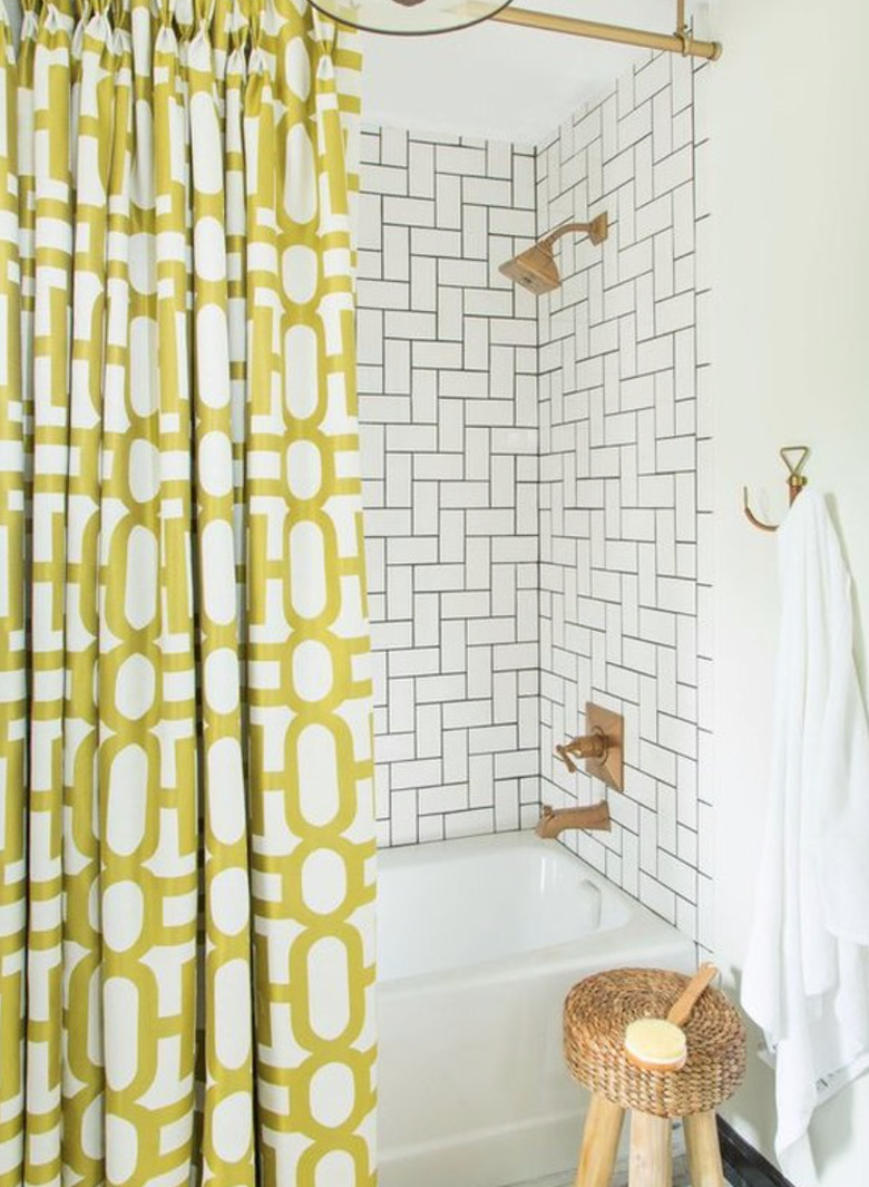 Subway tiles in a mix and match pattern in shower with yellow modern shower curtain.