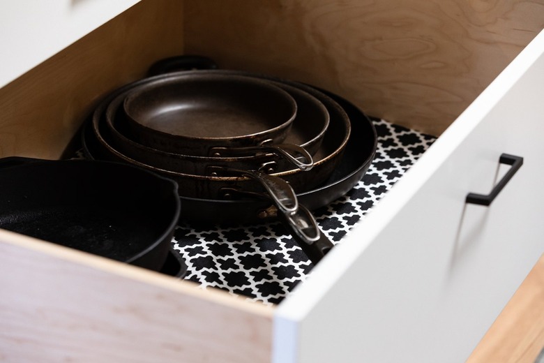 white kitchen drawer lined with patterned paper and stacked pans