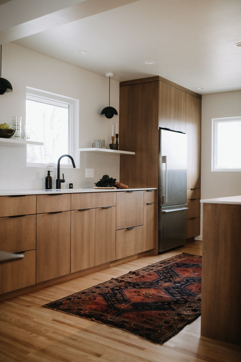 Champagne color kitchen with wood cabinets, red patterned runner, and floating white shelves