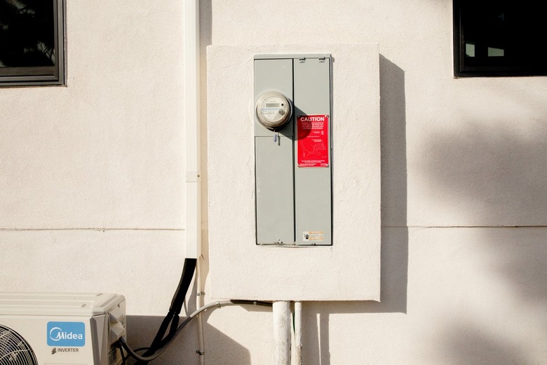 A gray water meter and circuit breaker box on a white wall.