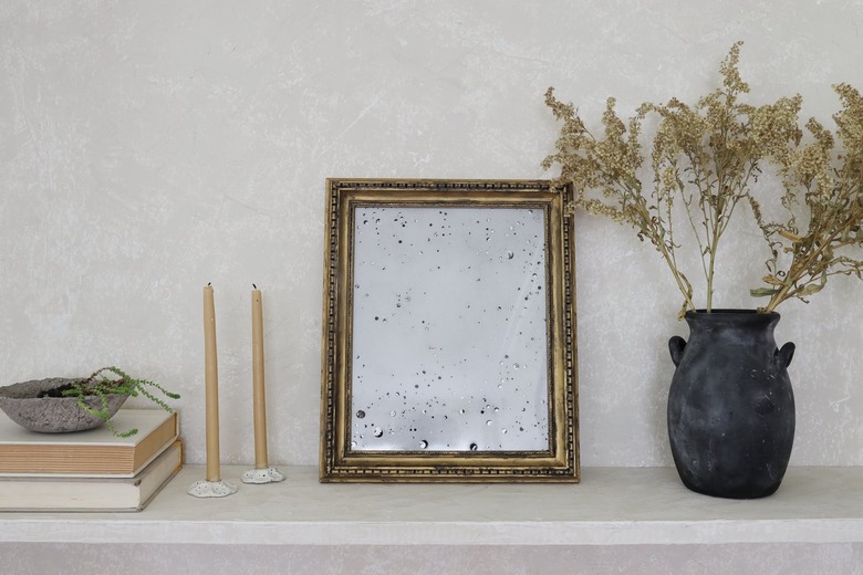 shelf with candlesticks, antique mirror, and vase with florals