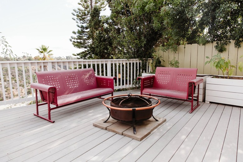 Red metal couches around fire pit on large white deck