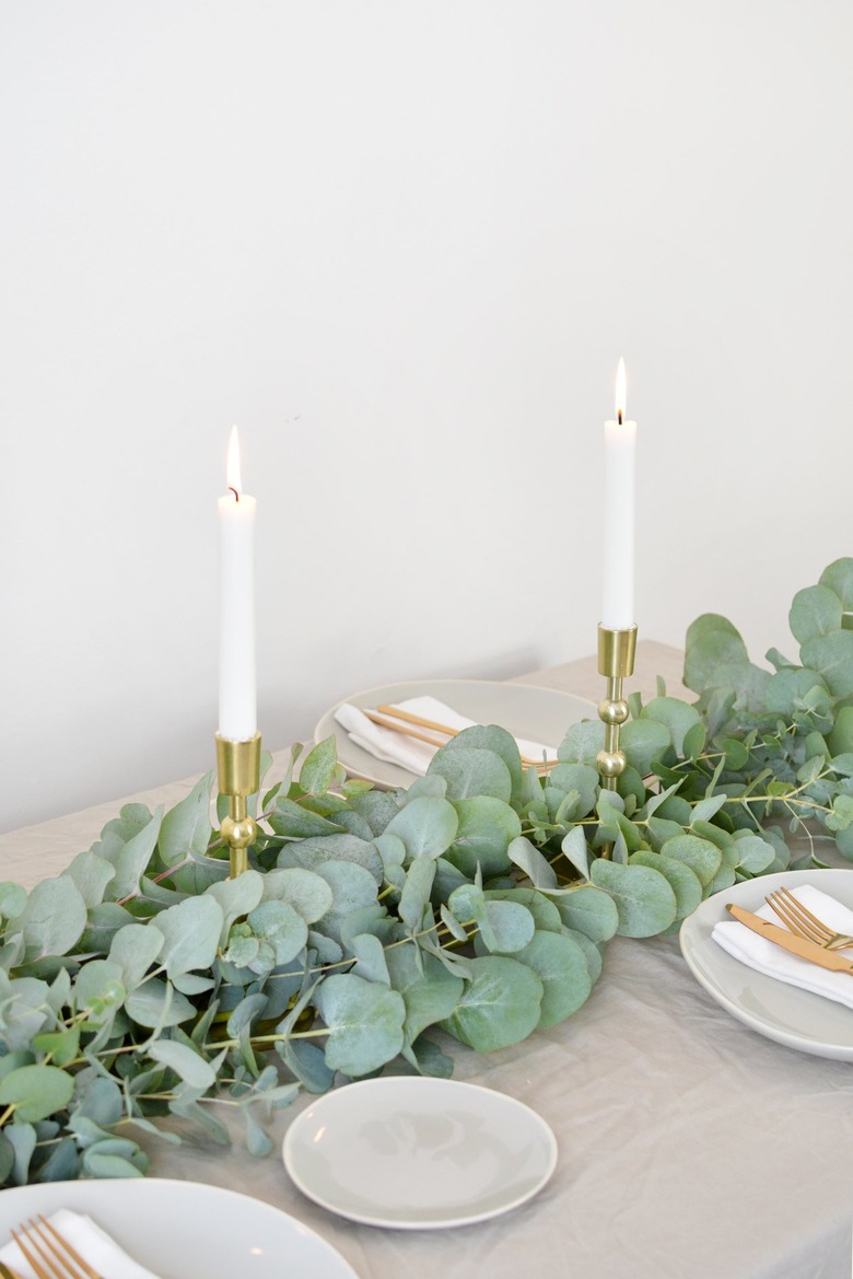 a table runner made from bunches of eucalyptus branches studded with tapers for Christmas centerpiece