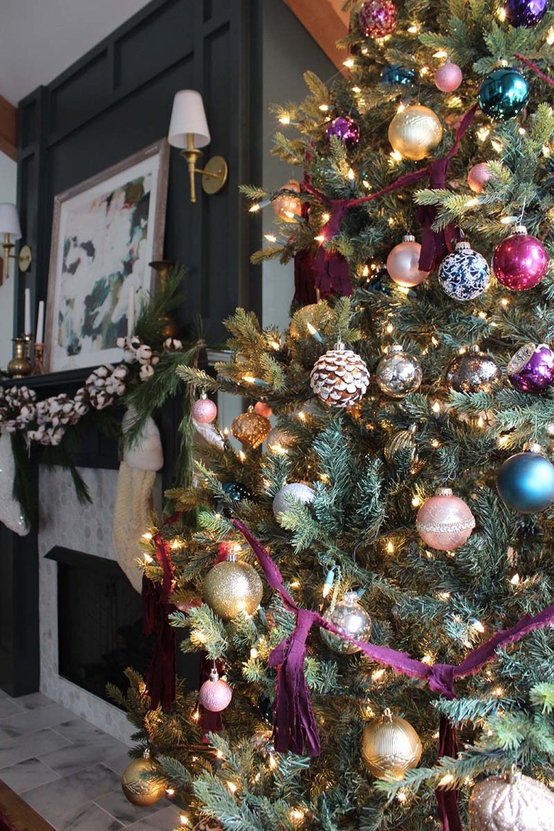 Dark living room with a Christmas tree with purple, gray, and gold ornaments.