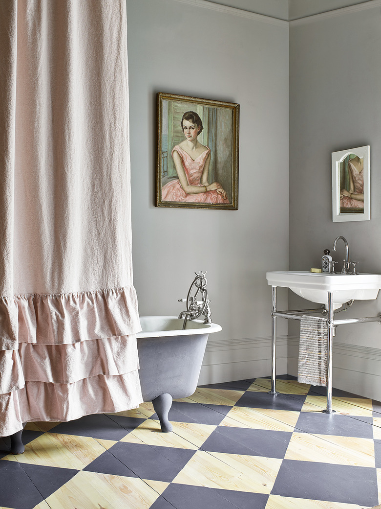 gray bathroom with checkered floors and clawfoot tub covered with a pink shower curtain