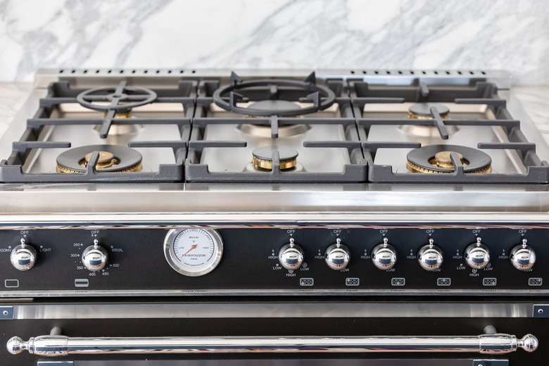 A stovetop with a gray-white granite backsplash