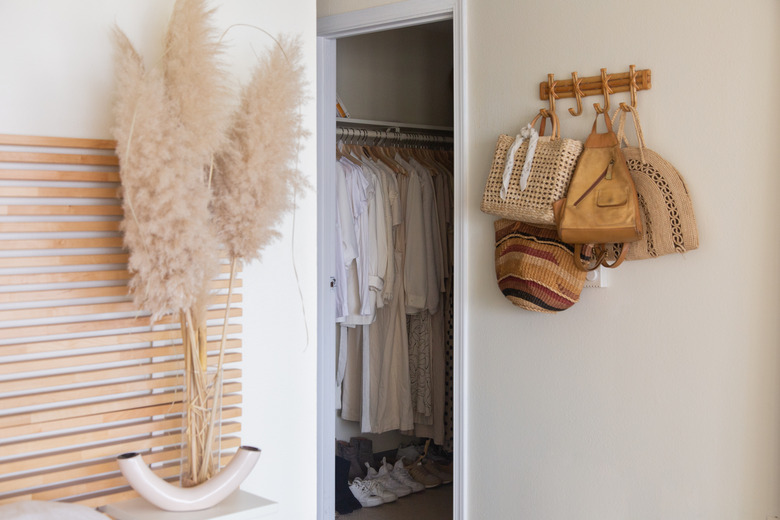 Bedroom closet design with hanging bags, pampas grass, and modern headboard