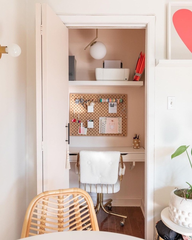 pink closet office with white swivel office desk and pendant light above