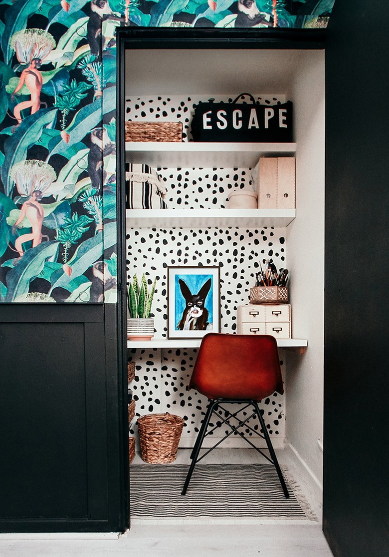 contemporary closet office with dalmation dot wallpaper inside the closet, red chair and tropical wallpaper on the outside