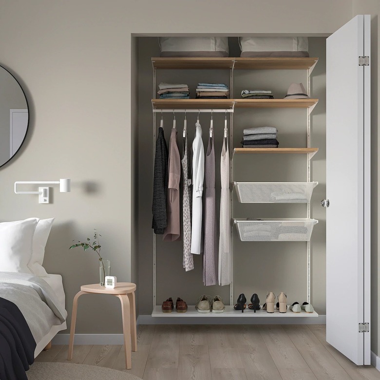 Bedroom with closet organizer unit, clothes, shoes, nightstand.