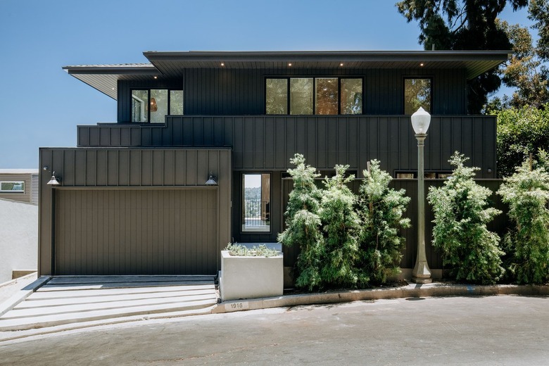 Black contemporary house in front of a sidewalk with a streetlamp